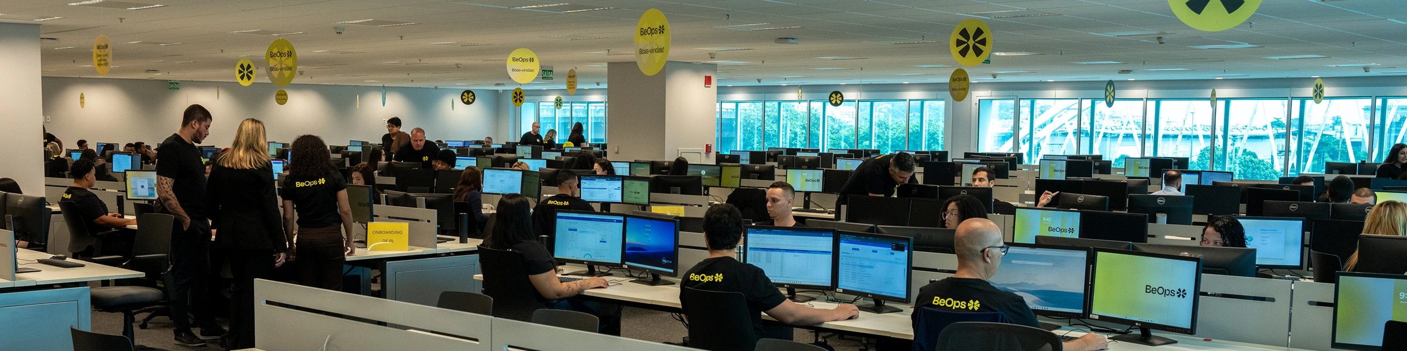 funcionários da BeOps em um escritório, sentados em frente às suas máquinas de trabalho.